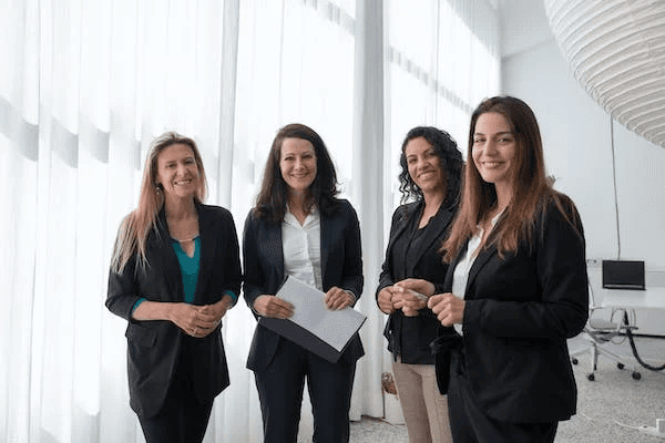 A group of women smiling wearing formal attire